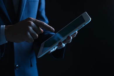 Photo of Man with modern tablet on black background, closeup