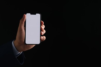 Photo of Man with modern smartphone on black background, closeup. Mockup for design
