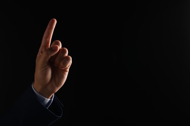 Photo of Man touching something on black background, closeup. Space for text