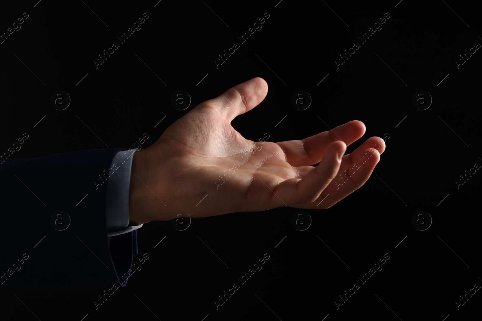 Photo of Man holding something on black background, closeup
