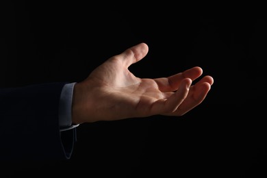 Photo of Man holding something on black background, closeup