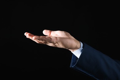 Photo of Man holding something on black background, closeup