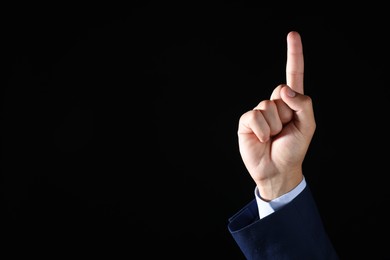 Photo of Man touching something on black background, closeup. Space for text