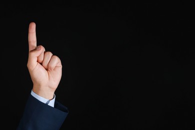 Photo of Man touching something on black background, closeup. Space for text