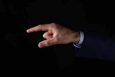 Photo of Man touching something on black background, closeup