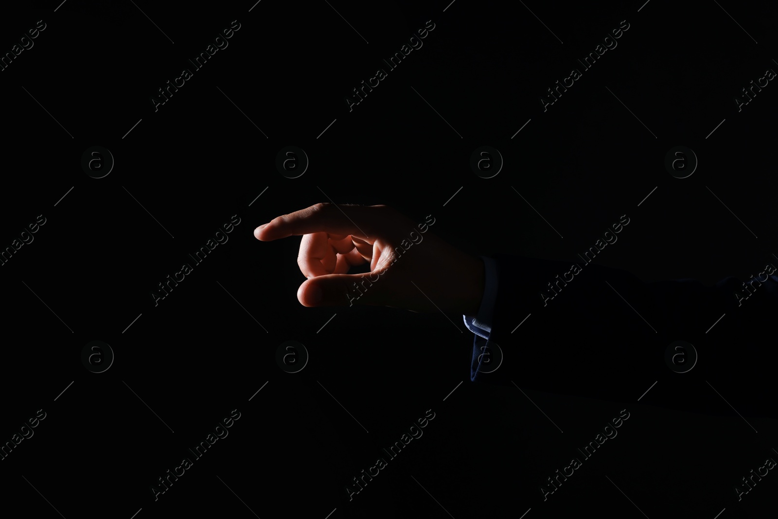 Photo of Man touching something on black background, closeup