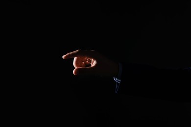 Photo of Man touching something on black background, closeup