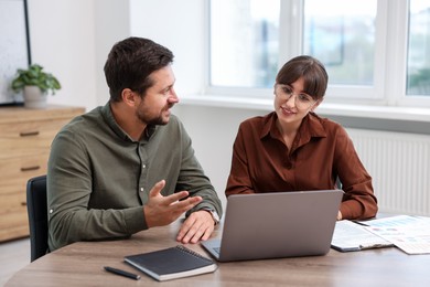 Photo of Consultant working with client at table in office. Business meeting