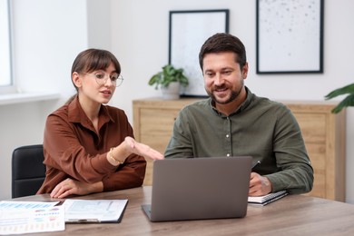 Photo of Consultant working with client at table in office. Business meeting