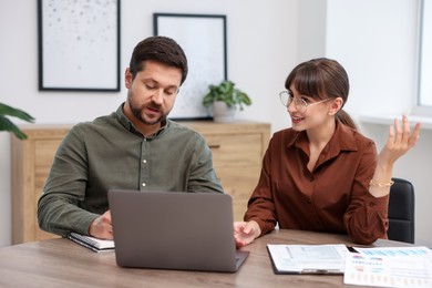 Photo of Consultant working with client at table in office. Business meeting