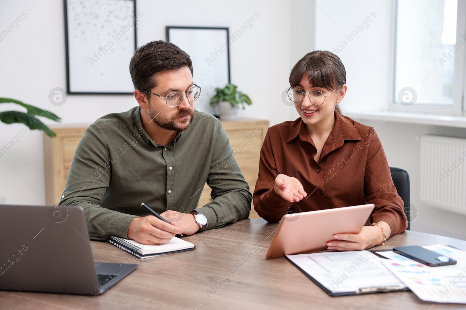 Consultant working with client at table in office. Business meeting Photo of Consultant working with client at table in office. Business meeting