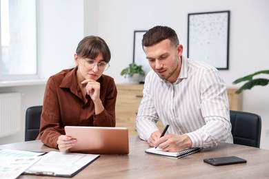 Photo of Consultant working with client at table in office. Business meeting