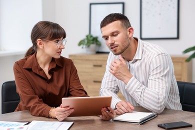 Photo of Consultant working with client at table in office. Business meeting