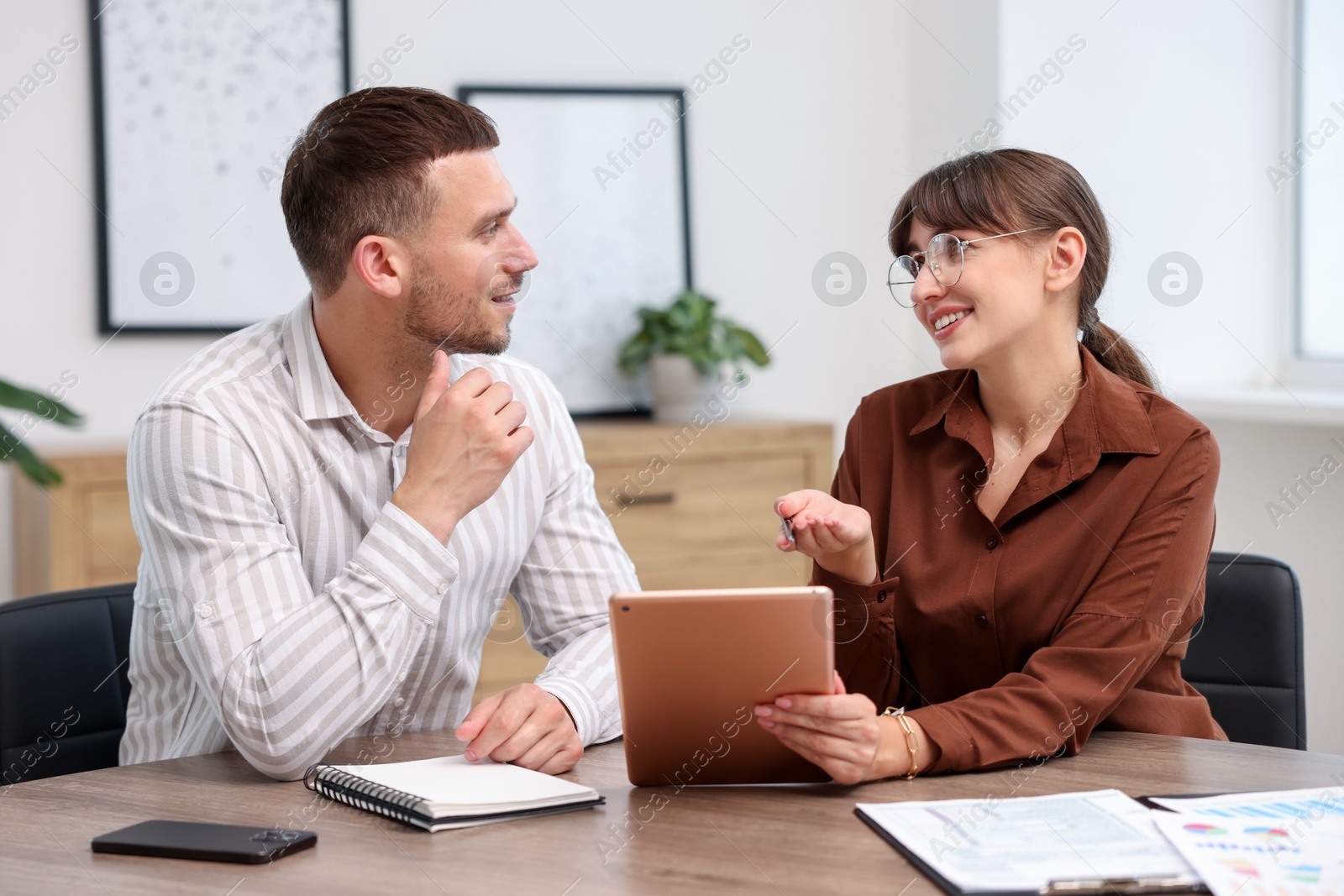 Photo of Consultant working with client at table in office. Business meeting