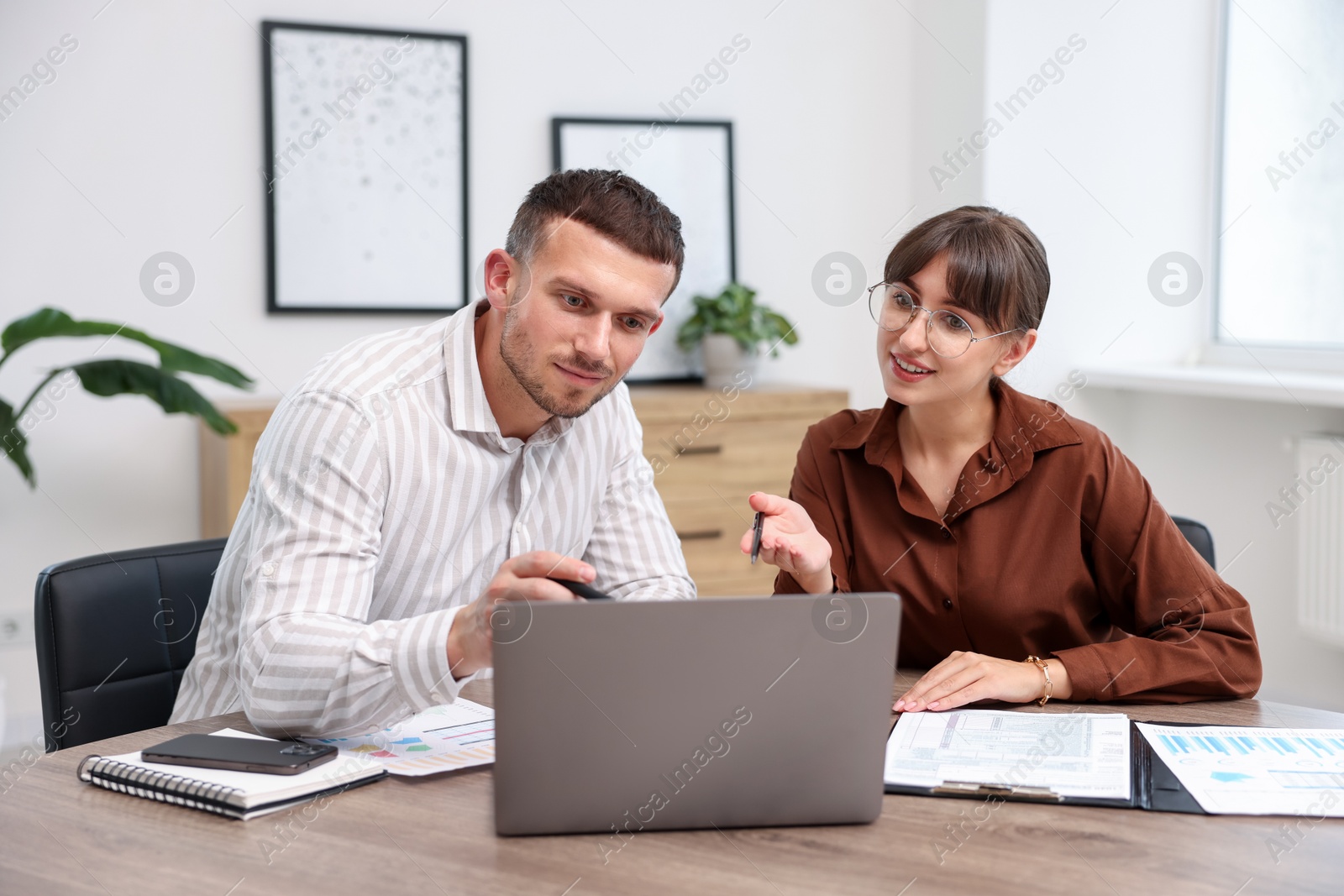 Photo of Consultant working with client at table in office. Business meeting