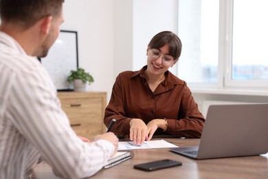 Photo of Consultant working with client at table in office. Business meeting