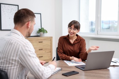 Photo of Consultant working with client at table in office. Business meeting