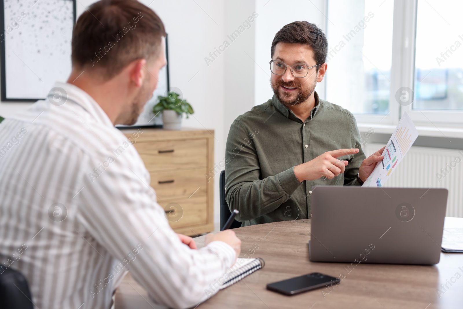 Photo of Consultant working with client at table in office. Business meeting