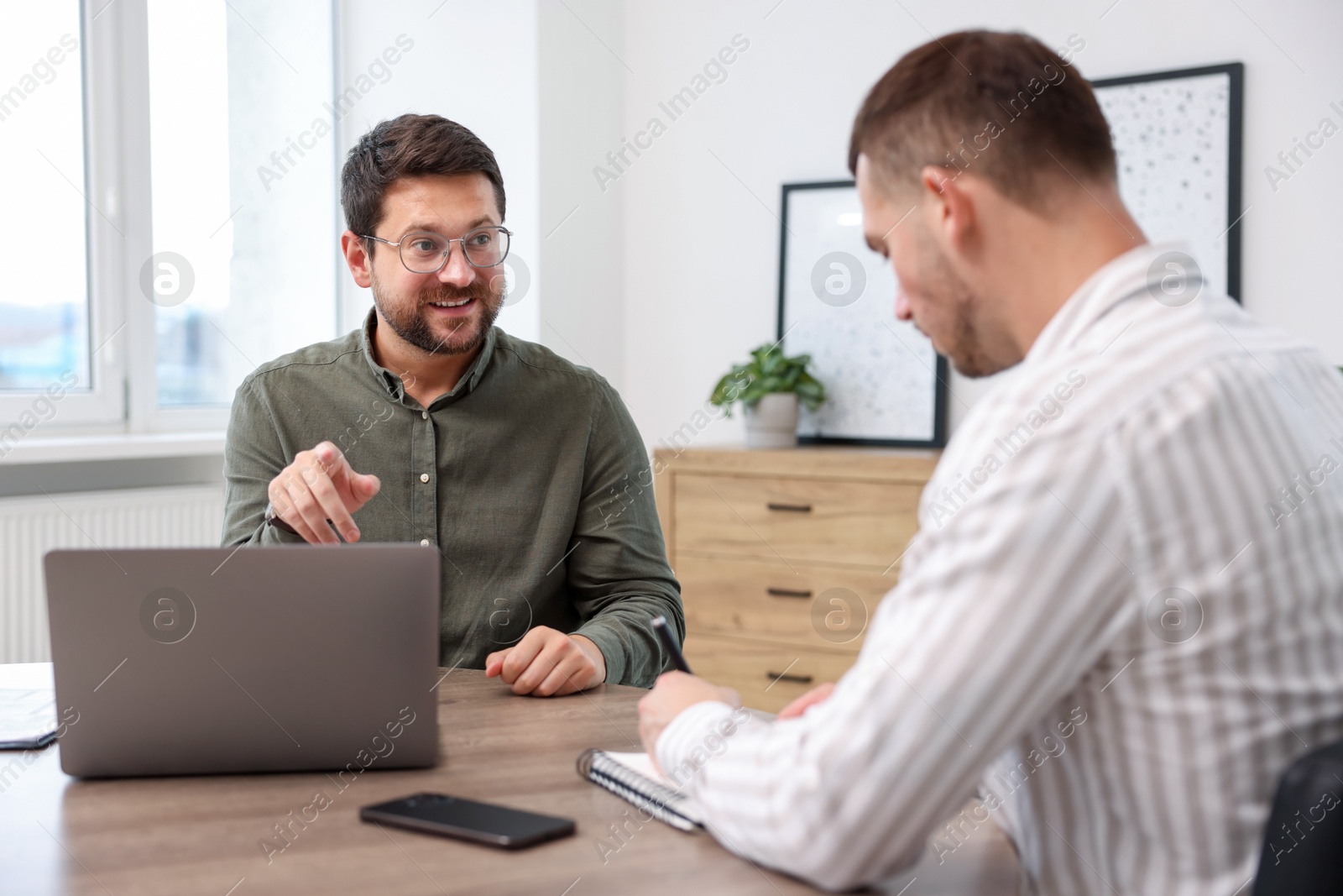 Consultant working with client at table in office. Business meeting Photo of Consultant working with client at table in office. Business meeting