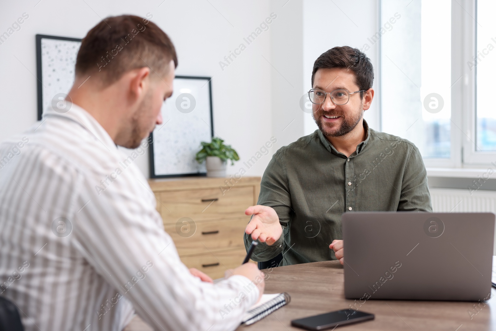 Consultant working with client at table in office. Business meeting Photo of Consultant working with client at table in office. Business meeting