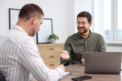 Photo of Consultant working with client at table in office. Business meeting