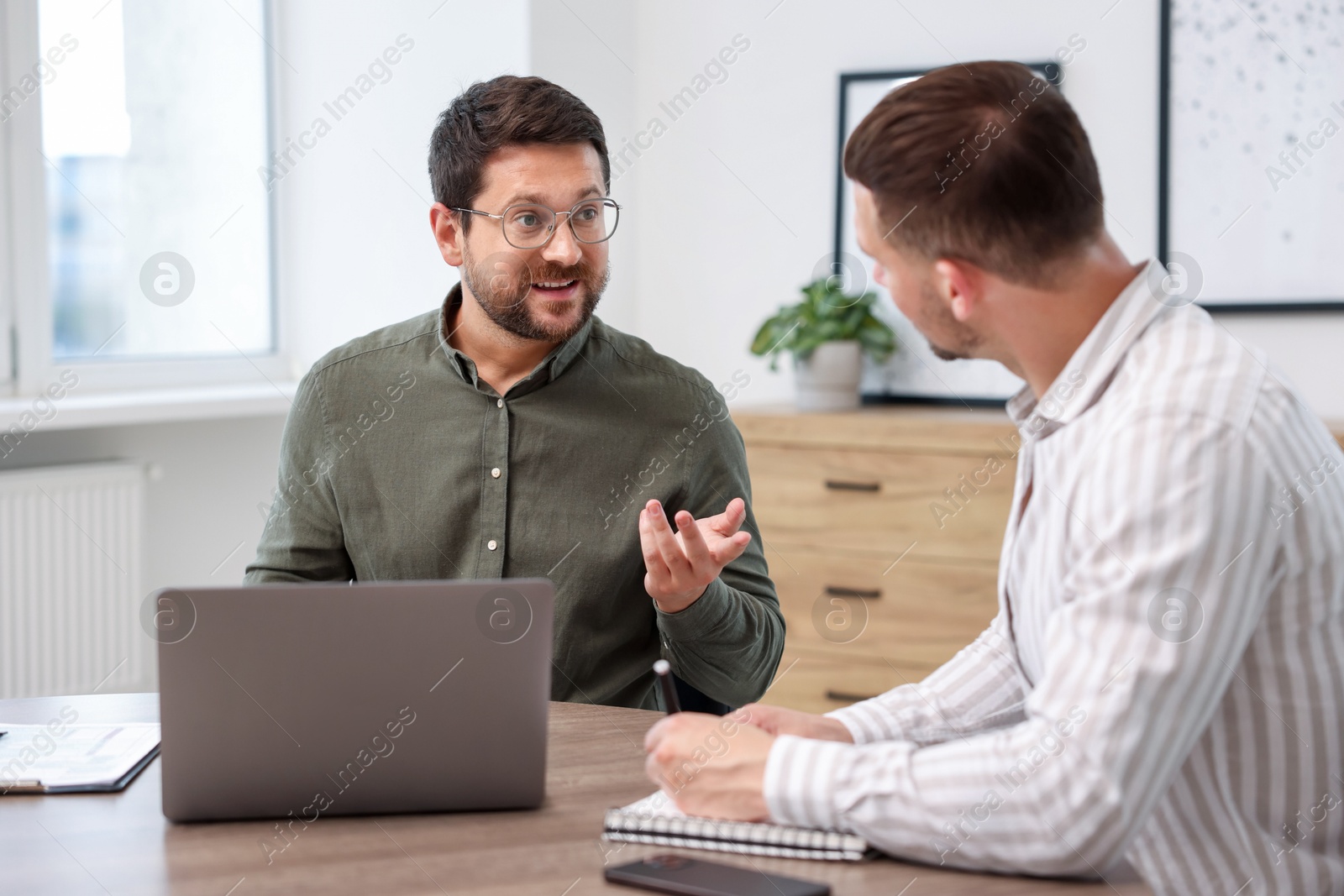 Consultant working with client at table in office. Business meeting Photo of Consultant working with client at table in office. Business meeting