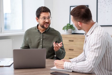 Photo of Consultant working with client at table in office. Business meeting
