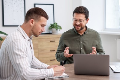 Photo of Consultant working with client at table in office. Business meeting