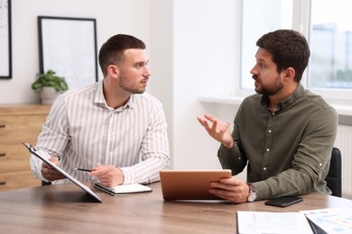 Photo of Consultant working with client at table in office. Business meeting