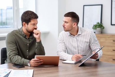 Photo of Consultant working with client at table in office. Business meeting