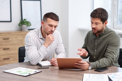 Photo of Consultant working with client at table in office. Business meeting