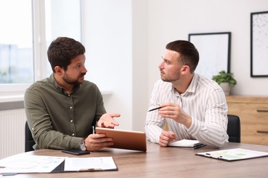 Photo of Consultant working with client at table in office. Business meeting