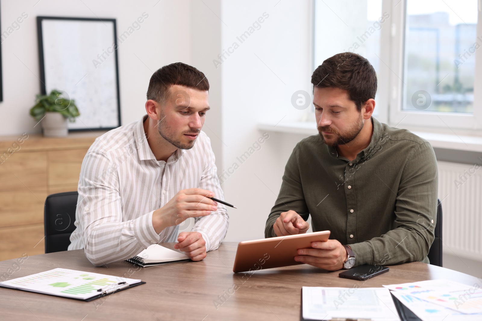 Consultant working with client at table in office. Business meeting Photo of Consultant working with client at table in office. Business meeting