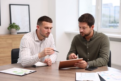 Photo of Consultant working with client at table in office. Business meeting