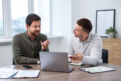 Photo of Consultant working with client at table in office. Business meeting