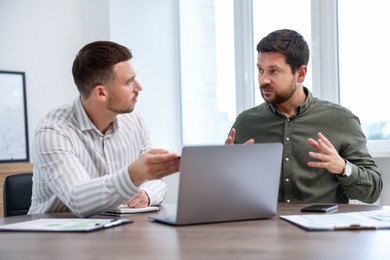 Photo of Consultant working with client at table in office. Business meeting