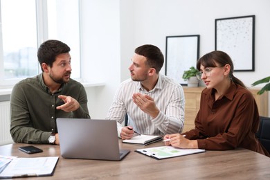 Photo of Couple having meeting with business consultant at table in office