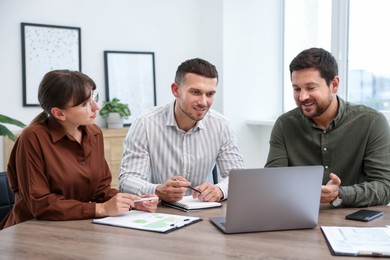 Photo of Couple having meeting with business consultant at table in office