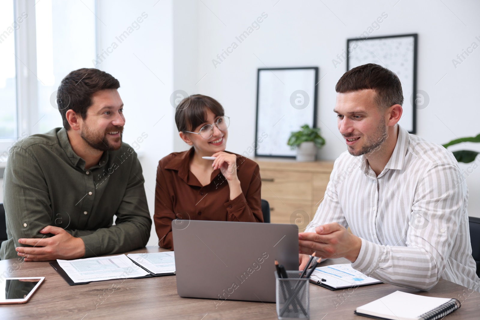 Photo of Couple having meeting with business consultant at table in office