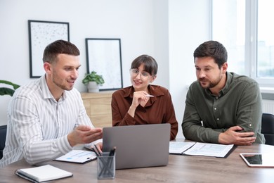 Photo of Couple having meeting with business consultant at table in office