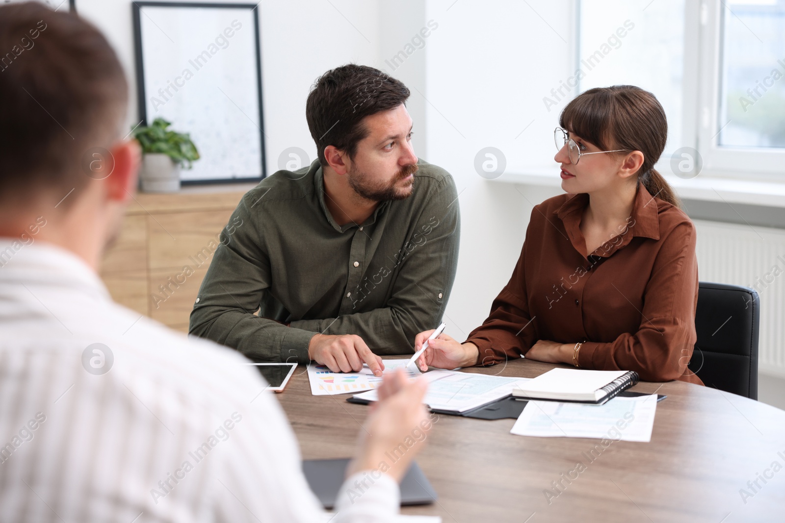 Photo of Couple having meeting with business consultant at table in office