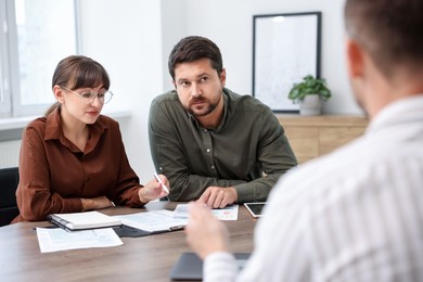 Photo of Couple having meeting with business consultant at table in office