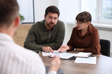 Photo of Couple having meeting with business consultant at table in office