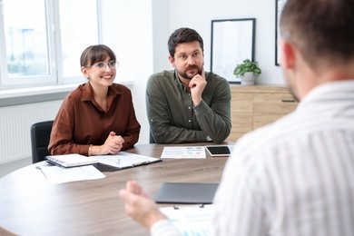 Photo of Couple having meeting with business consultant at table in office
