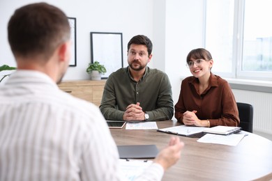 Photo of Couple having meeting with business consultant at table in office