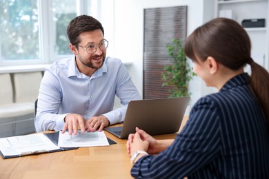 Photo of Consultant working with client at table in office. Business meeting