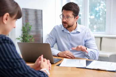 Photo of Consultant working with client at table in office. Business meeting