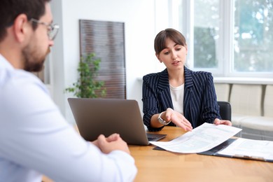 Photo of Consultant working with client at table in office. Business meeting