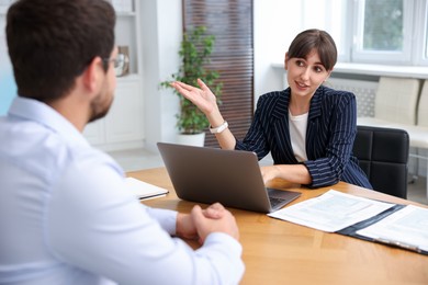 Photo of Consultant working with client at table in office. Business meeting