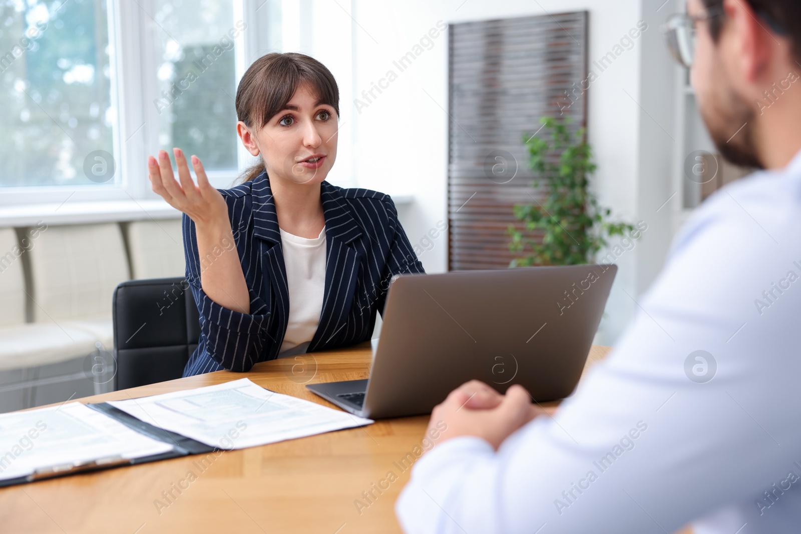 Photo of Consultant working with client at table in office. Business meeting